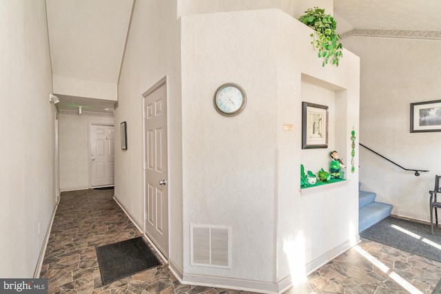 hallway with stairway, baseboards, visible vents, lofted ceiling, and stone finish floor