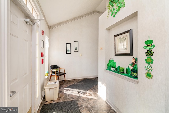 hallway with baseboards, lofted ceiling, and stone finish floor