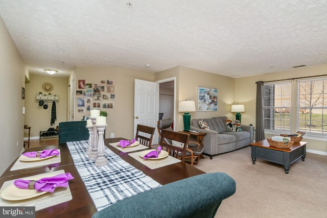 living area with baseboards, visible vents, a textured ceiling, and carpet