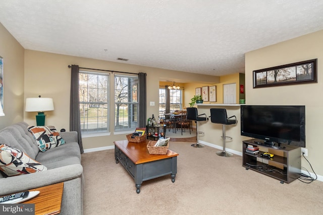 living room with visible vents, baseboards, a chandelier, carpet flooring, and a textured ceiling