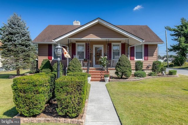 bungalow with a porch, a chimney, a front lawn, and roof with shingles