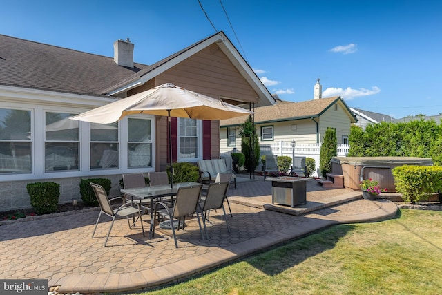 rear view of house with a hot tub, a lawn, a chimney, outdoor dining space, and a patio