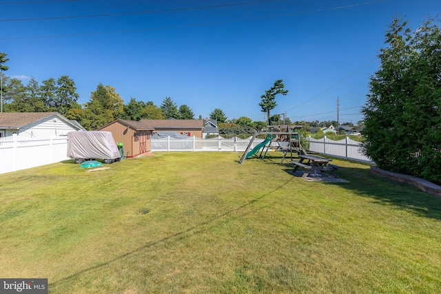 view of yard featuring an outbuilding, a fenced backyard, a shed, and a playground