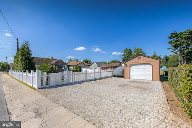 exterior space featuring a fenced front yard, driveway, a detached garage, and an outdoor structure