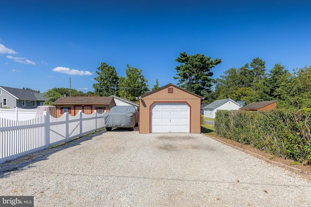 detached garage featuring gravel driveway and fence