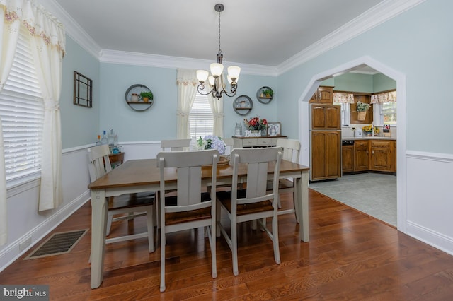 dining area featuring ornamental molding, wood finished floors, visible vents, and a chandelier