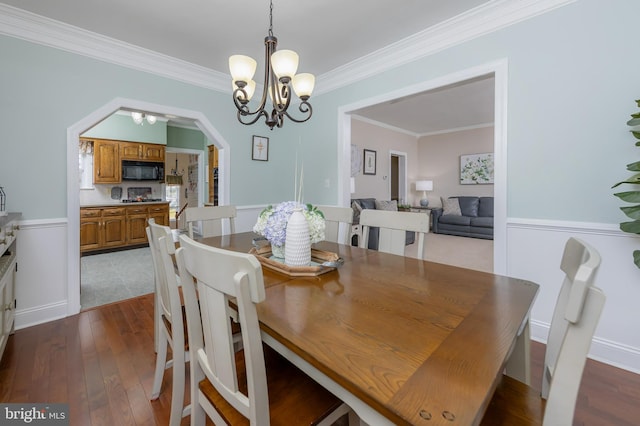 dining area with an inviting chandelier, crown molding, dark wood-type flooring, and arched walkways