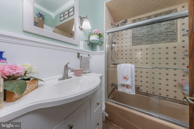 full bath with vanity, ornamental molding, combined bath / shower with glass door, and wainscoting