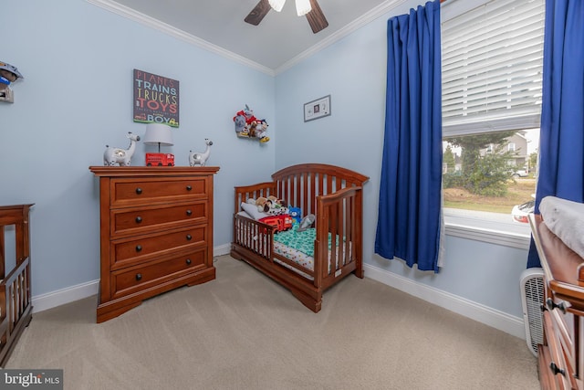 carpeted bedroom featuring baseboards, a crib, ceiling fan, and crown molding