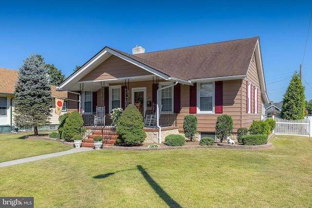 bungalow with a front yard, fence, covered porch, a shingled roof, and a chimney