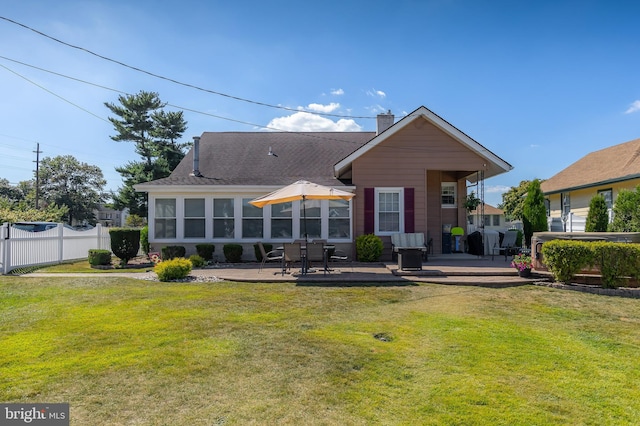 back of property with a patio area, a chimney, a yard, and fence