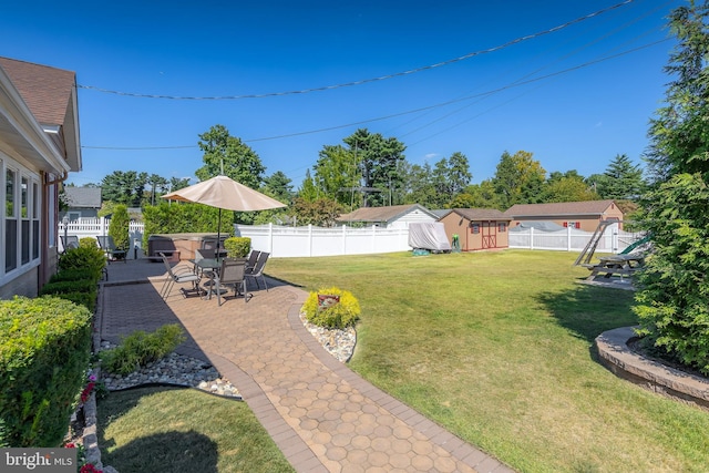 view of yard featuring a storage unit, a patio, an outbuilding, and a fenced backyard