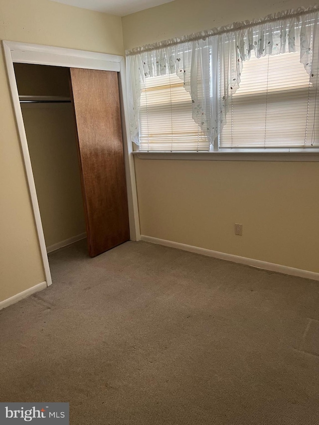 unfurnished bedroom featuring a closet, baseboards, and carpet flooring