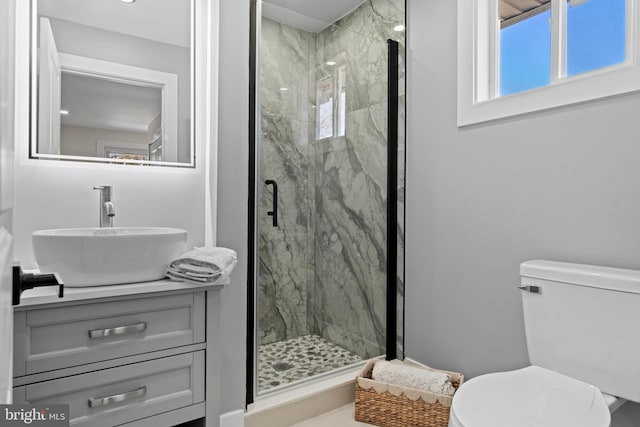 bathroom featuring a marble finish shower, toilet, and vanity