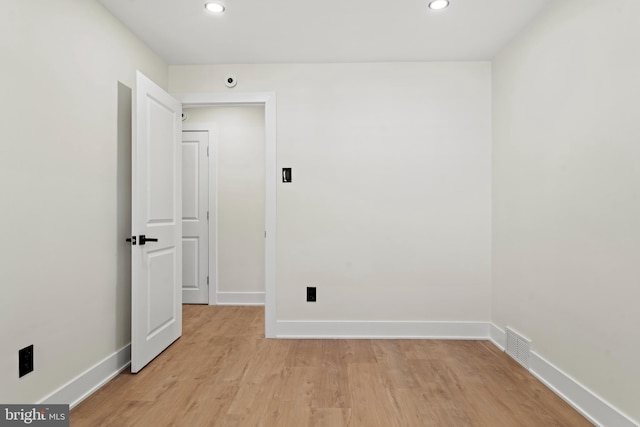 spare room with light wood-type flooring, visible vents, and baseboards