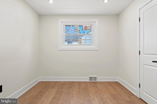 unfurnished room with light wood-type flooring, visible vents, and baseboards