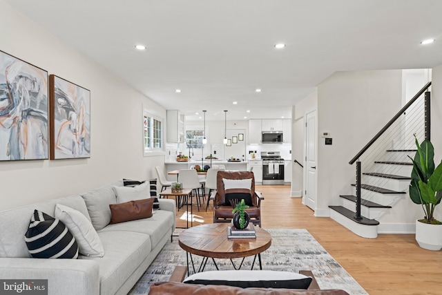 living area featuring stairway, recessed lighting, baseboards, and light wood-style floors