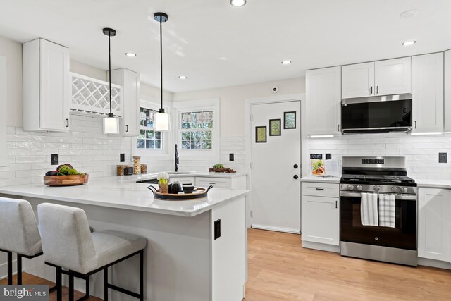 kitchen with white cabinetry, a breakfast bar area, light wood finished floors, and stainless steel appliances