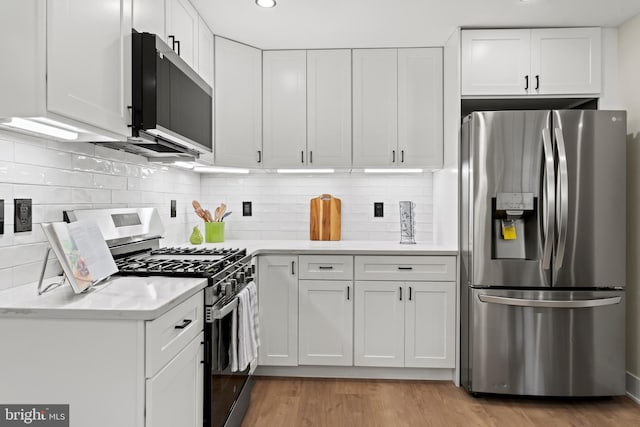 kitchen with light wood-type flooring, stainless steel appliances, white cabinetry, and light countertops