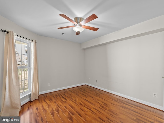 spare room featuring a ceiling fan, baseboards, and wood finished floors