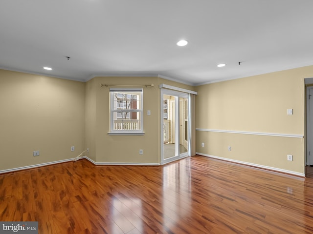 empty room with recessed lighting, crown molding, baseboards, and wood finished floors