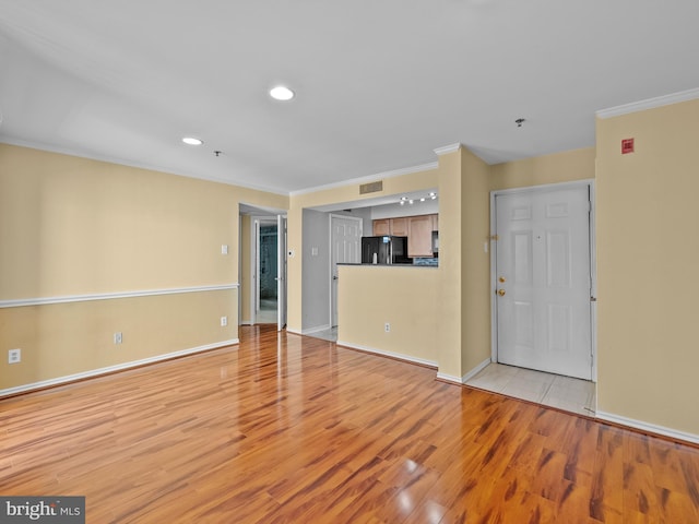 unfurnished living room featuring light wood-style flooring, visible vents, and ornamental molding