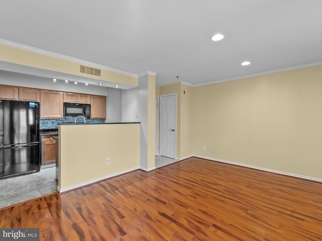 kitchen with visible vents, black appliances, backsplash, dark countertops, and light wood finished floors