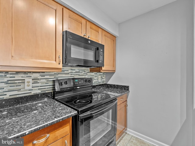 kitchen featuring light tile patterned floors, baseboards, dark stone counters, black appliances, and backsplash