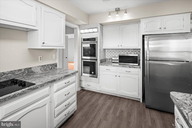 kitchen with light stone countertops, dark wood finished floors, stainless steel appliances, white cabinets, and backsplash