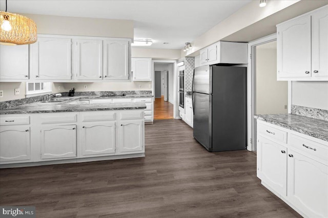 kitchen with white cabinetry, dark wood-style floors, stone countertops, and freestanding refrigerator