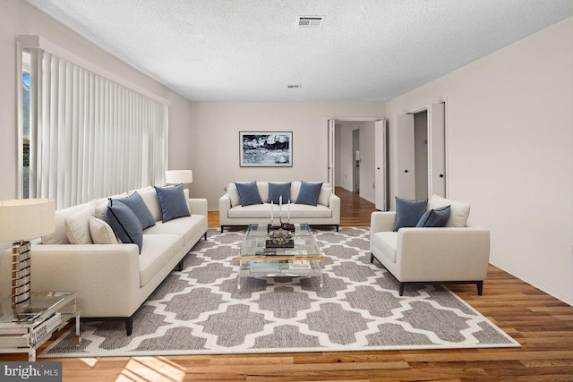 living room featuring wood finished floors, visible vents, and a textured ceiling