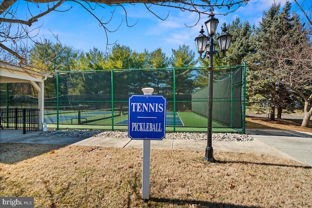 view of home's community featuring a tennis court and fence