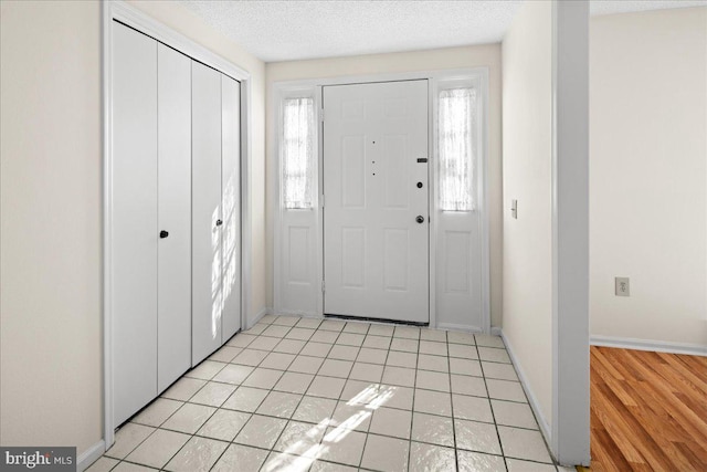 entrance foyer with light tile patterned flooring, baseboards, and a textured ceiling