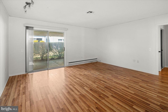 unfurnished room with a baseboard heating unit, visible vents, and wood finished floors