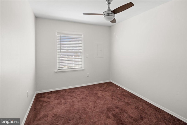 spare room with a ceiling fan, baseboards, and dark colored carpet