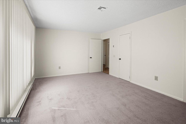 unfurnished bedroom featuring carpet, baseboards, visible vents, a textured ceiling, and baseboard heating