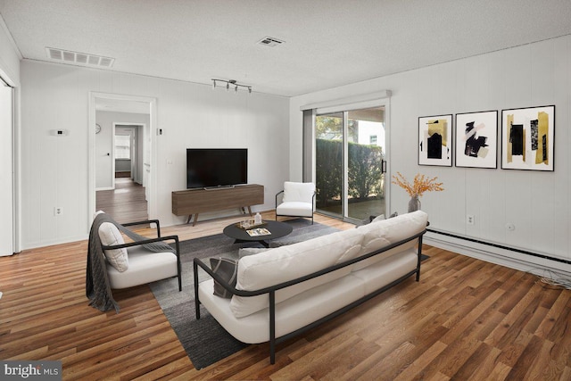 living room with visible vents, a baseboard radiator, a textured ceiling, and wood finished floors