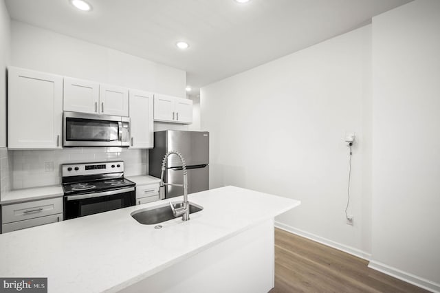 kitchen with a sink, light countertops, dark wood-type flooring, appliances with stainless steel finishes, and backsplash