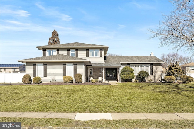 view of front of home with a shingled roof, a front lawn, and fence