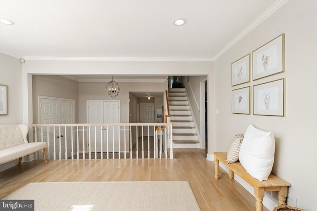 sitting room featuring stairway, a notable chandelier, light wood finished floors, and ornamental molding