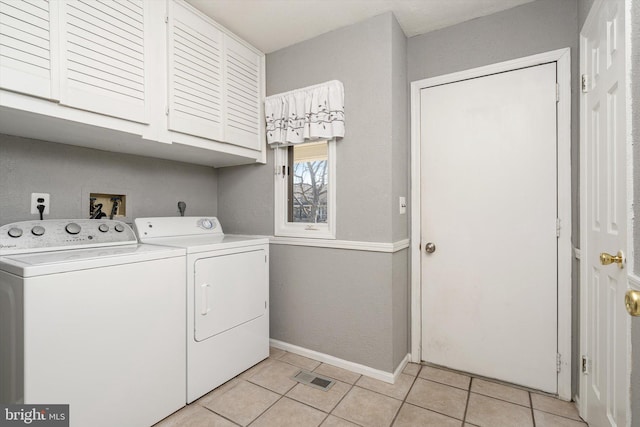 washroom with washing machine and clothes dryer, visible vents, baseboards, light tile patterned flooring, and cabinet space