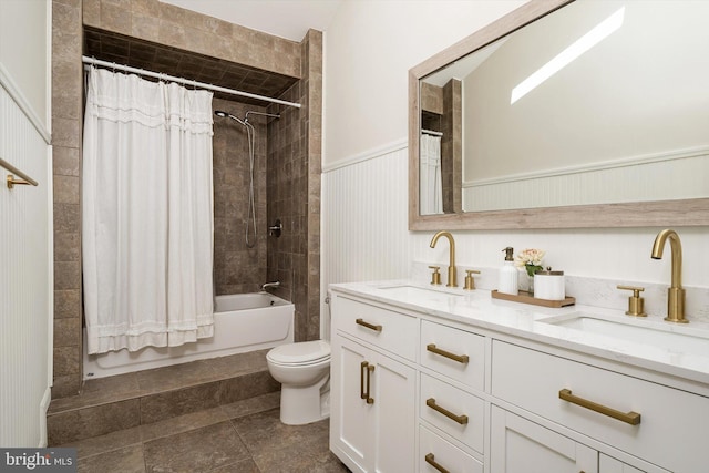 full bathroom featuring a sink, a wainscoted wall, toilet, and double vanity