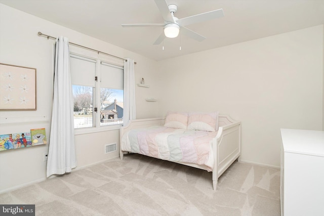 bedroom with visible vents, light colored carpet, baseboards, and ceiling fan