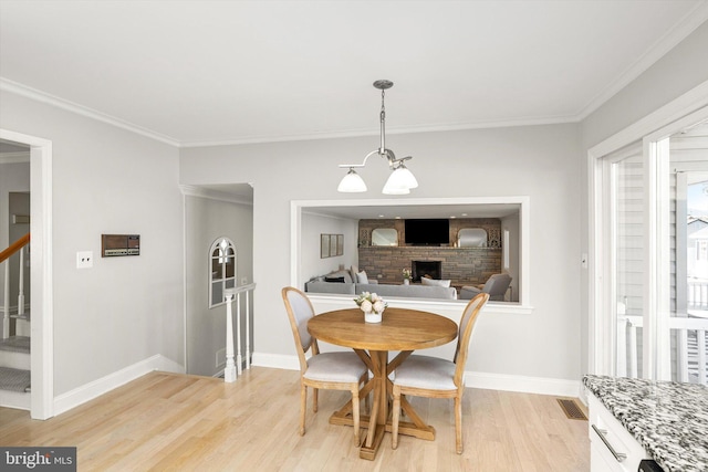 dining room with crown molding, stairway, baseboards, and light wood finished floors