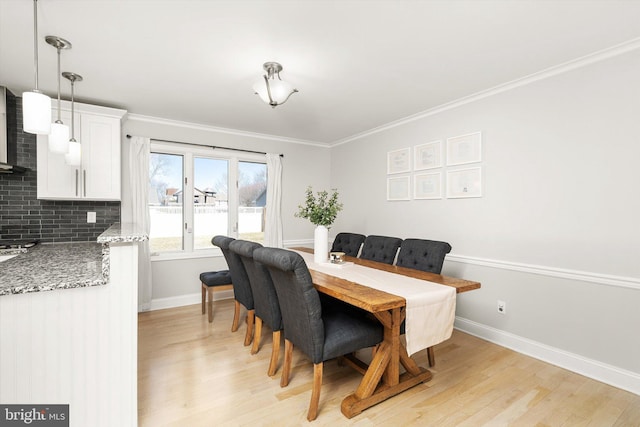 dining area with light wood finished floors, crown molding, and baseboards