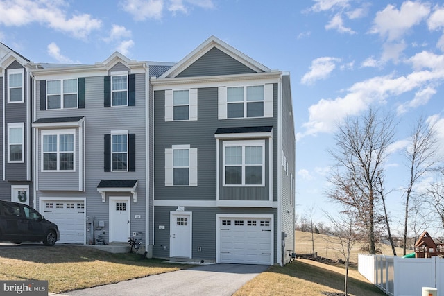 townhome / multi-family property with a garage, driveway, a front yard, and fence