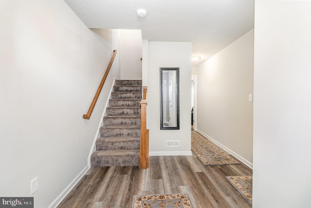 staircase with visible vents, baseboards, and wood finished floors