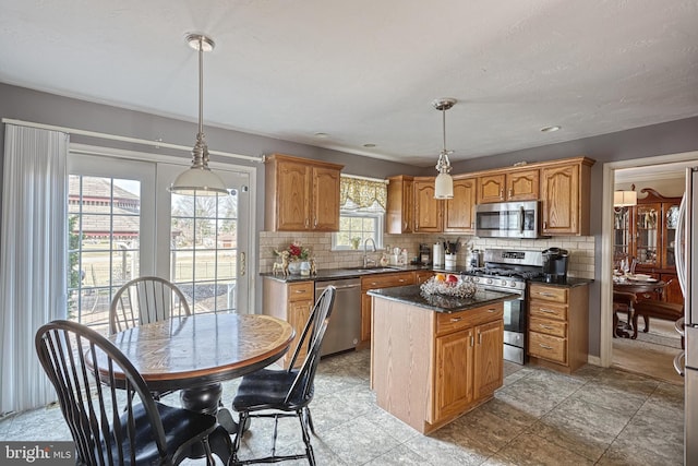 kitchen featuring tasteful backsplash, a kitchen island, appliances with stainless steel finishes, and a sink