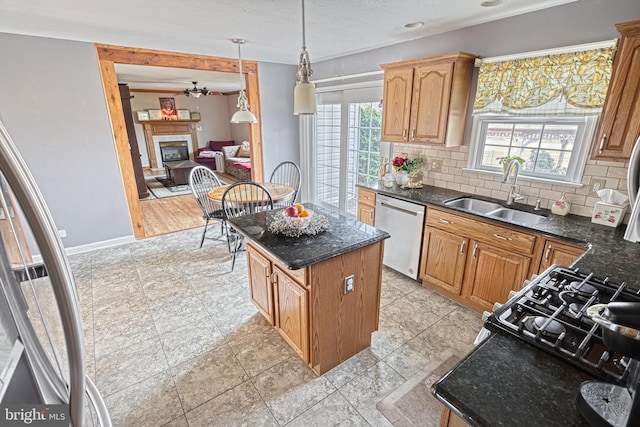 kitchen featuring a center island, dishwasher, decorative backsplash, a glass covered fireplace, and a sink