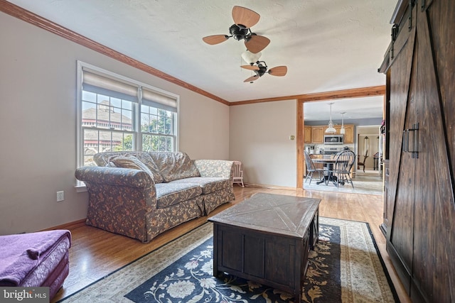 living room with crown molding, baseboards, light wood-type flooring, and ceiling fan